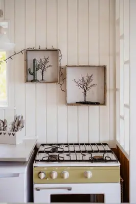 a kitchen stove with two pictures of trees on the wall at Summer House With Panoramic Views Of The Limfjord in Lihme