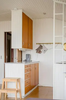 a kitchen with wooden cabinets and a wooden stool at Summer House With Panoramic Views Of The Limfjord in Lihme