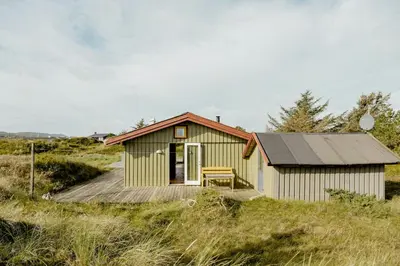 a small yellow house with a wooden deck at Family Home In Heather-Clad Landscape in Fjerritslev