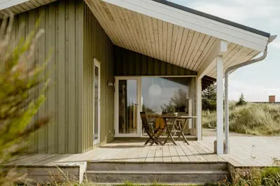 a green house with a deck and a table at Family Home In Heather-Clad Landscape in Fjerritslev