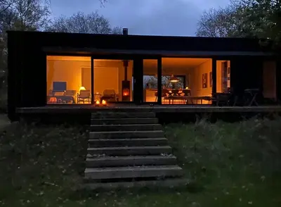 a small black house with glass doors and stairs at Architect-Designed House By Limfjord in Thyholm