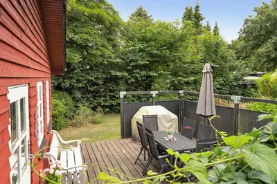 a deck with an umbrella and a table and an umbrella at Lifestyle Near Sea And Town in Nykøbing Mors