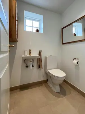 a bathroom with a white toilet and a window at Luxury With Pool In Dunes Near Løkken in Løkken