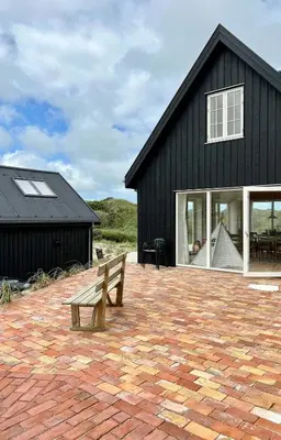 a black house with a bench in front of it at Luxury With Pool In Dunes Near Løkken in Løkken