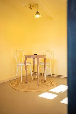 a table and chairs in a room with a yellow wall at Historic Fisherman's Gem With Twist In Klitmøller in Torsted