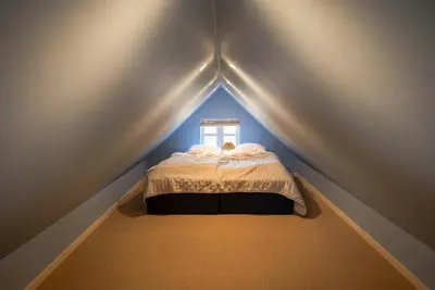 a small bedroom with a bed in a roof at Historic Fisherman's Gem With Twist In Klitmøller in Torsted
