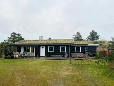 a blue house with a porch and a yard at Creative Family House Near Blokhus Beach in Blokhus