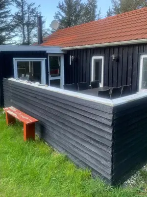 a house with a deck with chairs and a bench at North Sea's Expanse Near Vorupør in Thisted