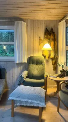 a living room with a chair and a table at Holiday Home In Tranum Forest in Brovst