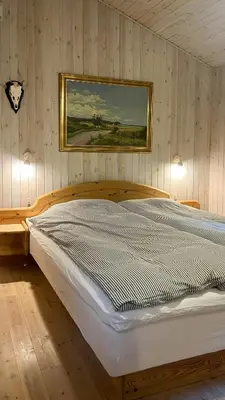 a bedroom with a wooden bed with a painting on the wall at Holiday Home In Tranum Forest in Brovst