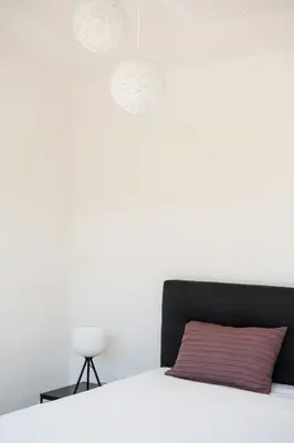 a bedroom with white walls and a bed with a red pillow at Architect-Designed House Close To The North Sea in Vestervig