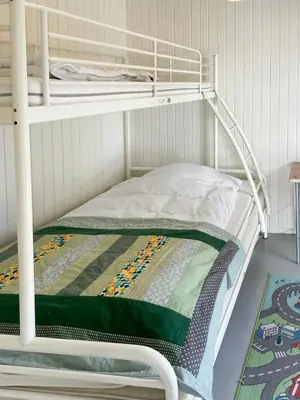 a white bunk bed with a green blanket on it at Personlighed Arkitekttegnet Hus Ved Spøttrup in Spottrup
