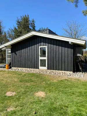 a black house with a grass yard in front of it at Personlighed Arkitekttegnet Hus Ved Spøttrup in Spottrup