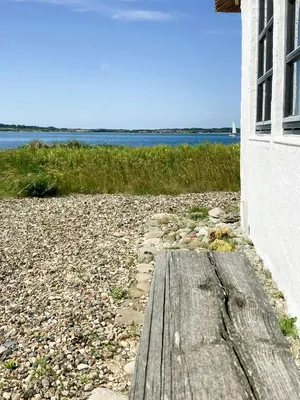 a wooden boardwalk on a beach next to a building at Historic House With Fjord View On Venø in Vemb