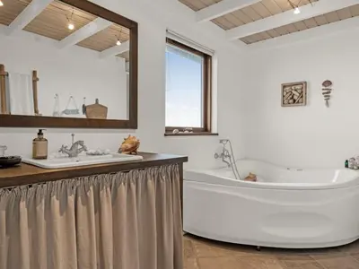 a large white bathroom with a tub and a sink at Holiday Home Bjerund - 300m from the sea by Interhome in Løkken