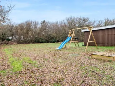 a playground with a blue slide in a yard at Holiday Home Star - 200m to the fjord by Interhome in Farsø