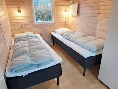 two beds in a room with wooden walls at Toftum Bjerge Camping & Cottages in Humlum