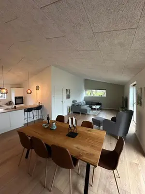 a dining room and living room with a wooden table at Moderne nybygget in Holstebro