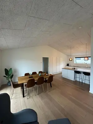 a dining room and kitchen with a wooden table and chairs at Moderne nybygget in Holstebro