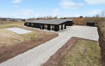 a house with a black roof on a field at Nice Home In Højslev With Sauna in Højslev