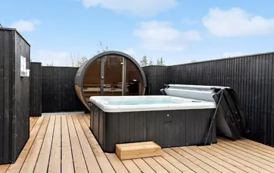 a hot tub on a deck with a wooden fence at Nice Home In Højslev With Sauna in Højslev