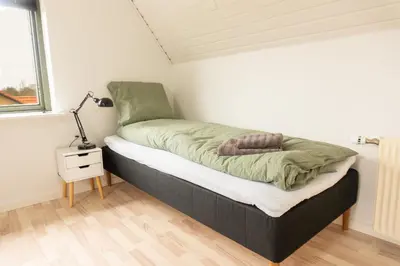a bed in a room with a lamp next to a window at Villa Holstebro in Holstebro
