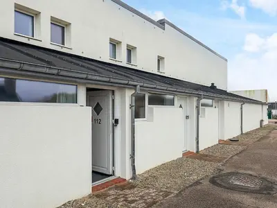 a white building with white doors and a street at 6 person holiday home in Brovst in Brovst