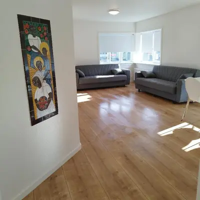 a living room with two couches and a painting on the wall at Hyggelig lejlighed i stille by in Vemb