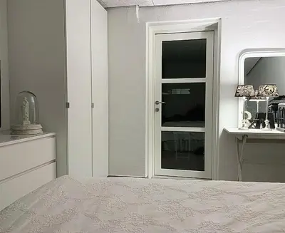 a white bedroom with a bed and a window at Blokhus Beach House in Blokhus