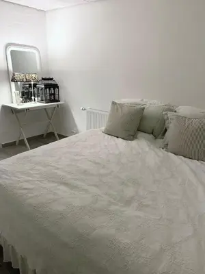 a white bed in a white room with a mirror at Blokhus Beach House in Blokhus