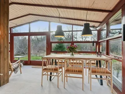 a dining room with a table and chairs and windows at Charming Wooden Summer House In Trend in Løgstør