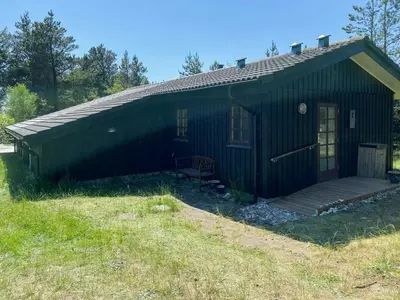 a small green building with a porch and a deck at Relaxed Summer House By The North Sea in Blokhus