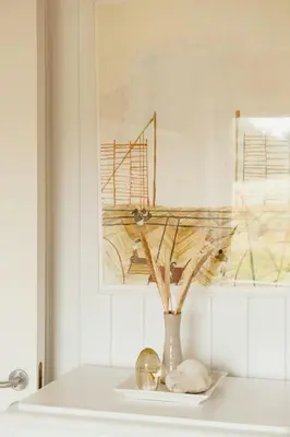 a vase with branches in it sitting on a table at Nordic 70S Gem Amidst The Dunes in Blokhus