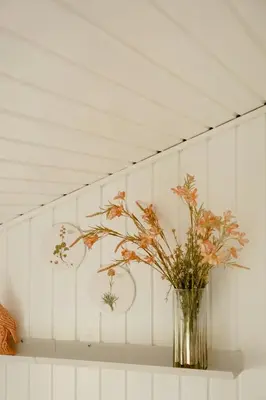 a vase with flowers on a shelf in a room at Nordic 70S Gem Amidst The Dunes in Blokhus