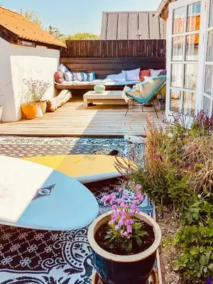 a patio with a surfboard and flowers on a deck at In Cold Hawaii With Beach In Backyard in Torsted