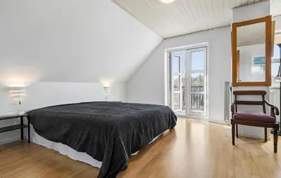 a bedroom with a bed and a chair in it at Beautiful Home In Nibe With Sauna in Nibe
