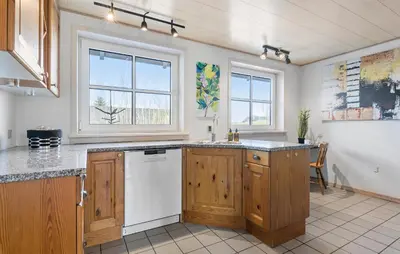 a kitchen with wooden cabinets and a white dishwasher at Beautiful Home In Nibe With Sauna in Nibe