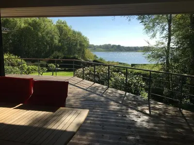 a deck with a view of a lake from a house at Holiday Home Nico - 70m to the inlet by Interhome in Roslev