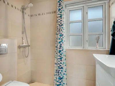 a bathroom with a shower and a toilet and a window at Holiday Home Toska - 3km from the sea by Interhome in Blokhus