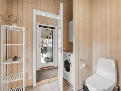 a bathroom with a toilet and a washing machine at Holiday Home Antero - 500m to the fjord by Interhome in Spottrup