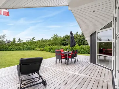 a wooden deck with a table and chairs on it at Holiday Home Antero - 500m to the fjord by Interhome in Spottrup