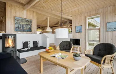 a living room with a table and chairs and a fireplace at Cozy Home In Saltum With House Sea View in Saltum