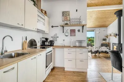 a kitchen with white cabinets and a wooden floor at Charming little cottage in Roslev