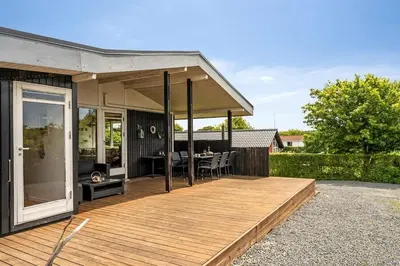 a wooden deck with a dining table on a house at Charming little cottage in Roslev