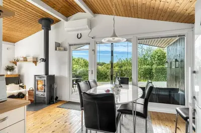 a kitchen and dining room with a glass table and chairs at Charming little cottage in Roslev