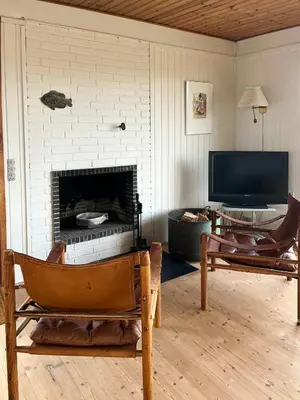a living room with a fireplace and a television at Wooden House In The Dunes Close To The Sea in Pandrup