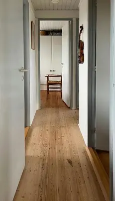 a hallway with a wooden floor and a table at Wooden House In The Dunes Close To The Sea in Pandrup