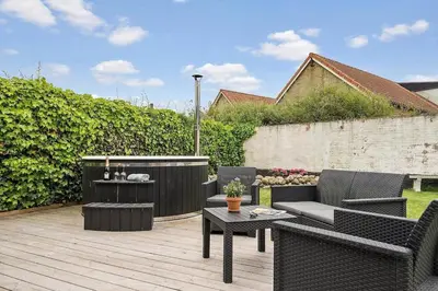 a patio with chairs and a table on a wooden deck at Newly renovated house in the center in Thyborøn
