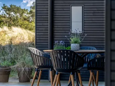 a wooden table with four chairs on a patio at Holiday Home Eriksine - 750m from the sea by Interhome in Løkken