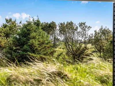 a field of grass with trees in the background at Holiday Home Eriksine - 750m from the sea by Interhome in Løkken